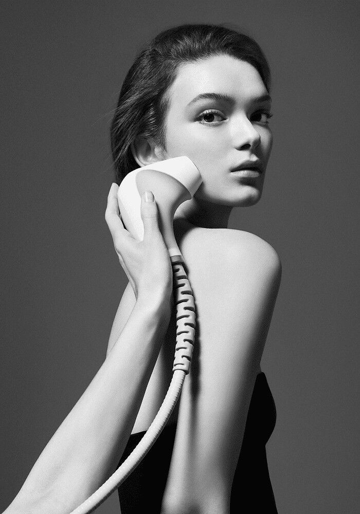 Photographie en noir et blanc d'une jeune femme recevant un soin Carita avec la technologie pro.morphose sur la joue.