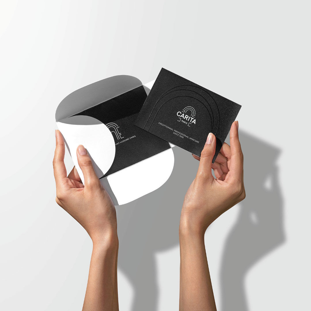 Mains ouvrant un etui noir avec une carte cadeau noire.