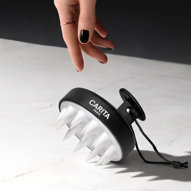 Deux mains tiennent une brosse a cheveux sur un fond blanc uni, mettant ainsi en valeur le design et la fonctionnalite de la brosse.