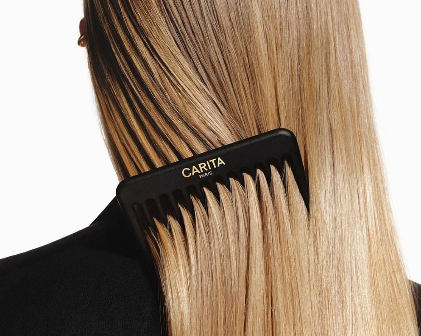 Peigne noir Carita demelant de longs cheveux blonds lisses.