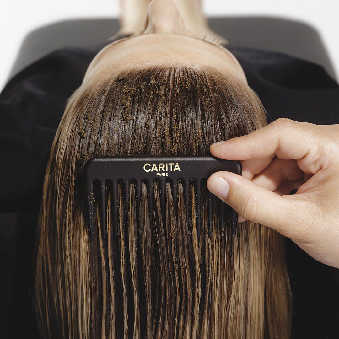 Peigne Carita dans des cheveux avec gommage Le Renovateur.