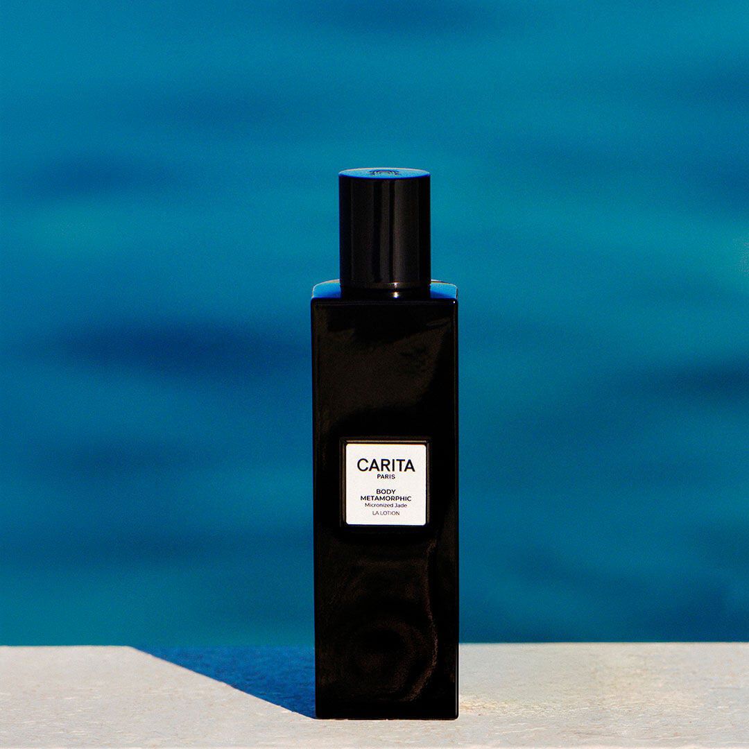 Flacon noir de lotion Body Metamorphic sur fond bleu azur.