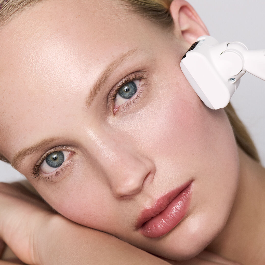 Femme recevant un soin du visage avec un appareil blanc.