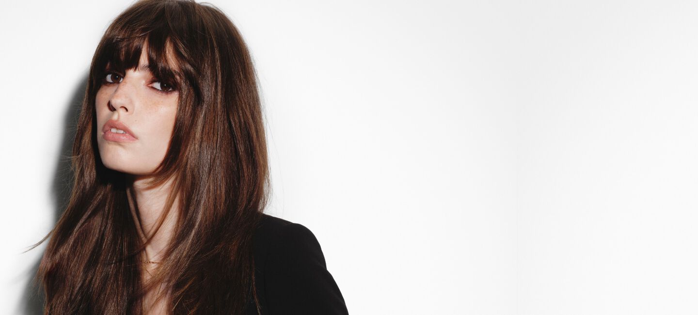 Femme brune a frange avec un brushing soyeux Hair Rejuvenic.