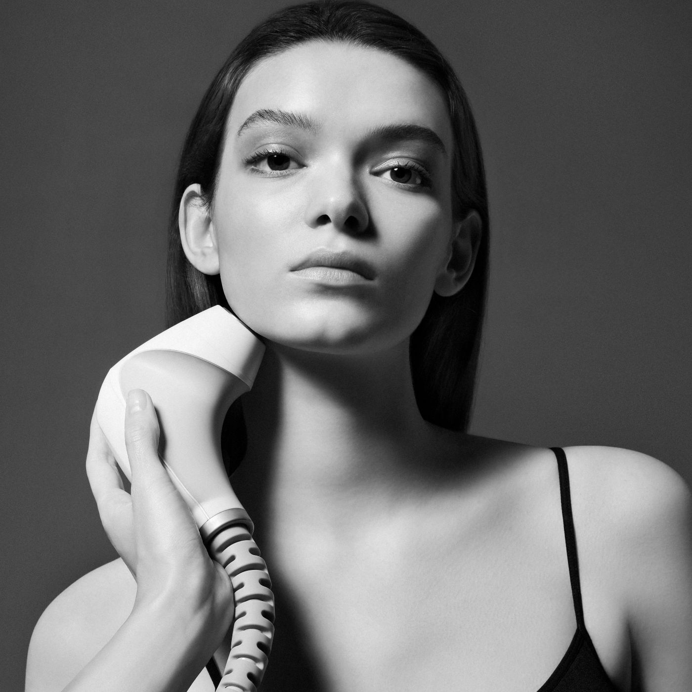 Gros plan en noir et blanc d'une femme utilisant un appareil de soin sur sa machoire.