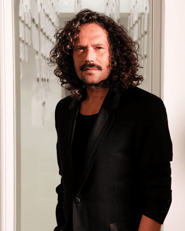 Portrait souriant du coiffeur David Lucas en costume noir.