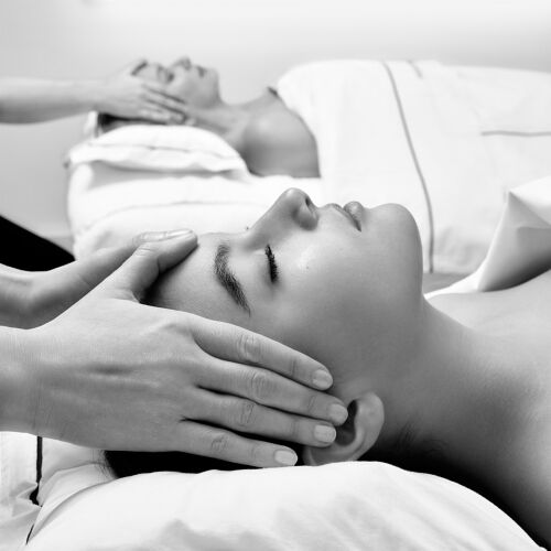 Deux personnes recoivent des massages faciaux relaxants dans un spa serein, en noir et blanc, evoquant la tranquillite et le bien-etre partage.
