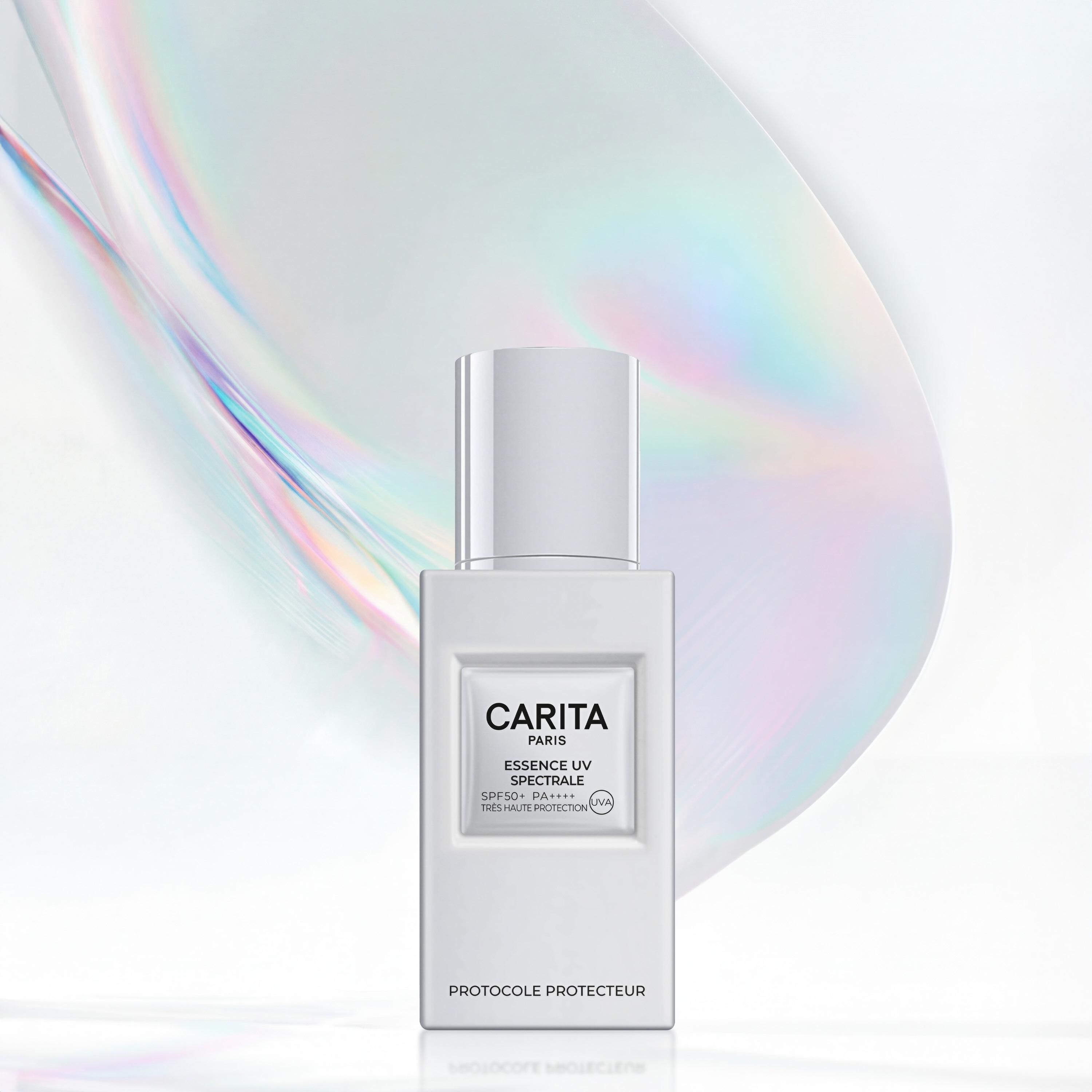 Flacon d’ Essence UV Spectrale de Carita devant un halo iridescent. Un visuel moderne qui illustre la barriere protectrice et l'eclat lumineux offerts par ce soin solaire de luxe. ​