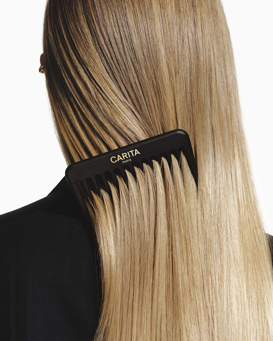 Peigne noir Carita demelant de longs cheveux blonds lisses.