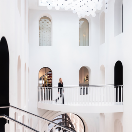 Interieur blanc moderne et elegant avec balcon courbe fluide et main courante sombre. Ouvertures cintrees et decorations circulaires uniques creent une architecture sophistiquee et dynamique.