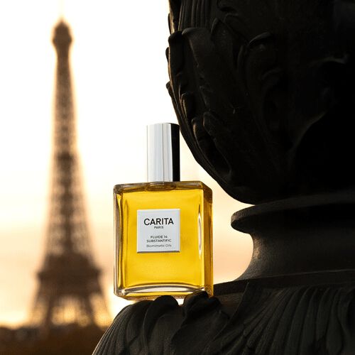 Pot de Carita Fluide 14 Substantific pose sur un element architectural sombre et elegant, avec la Tour Eiffel baignee par une lumiere doree de lever ou de coucher de soleil en arriere-plan, evoquant une scene parisienne sophistiquee.