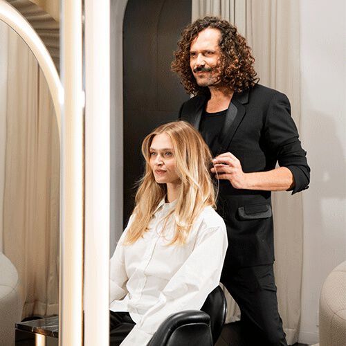 Femme portant une chemise blanche, assise confortablement sur un canape.